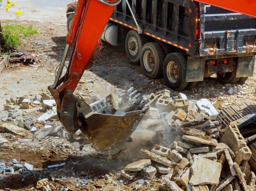Excavator loads construction waste into of material for disposal from construction a home renovation